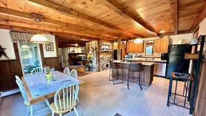 A spacious kitchen with wooden cabinets, a central island, and a stone accent wall. - Tall Pines Retreat, Somesville|Mt. Desert. 15 min to Bar Harbor, 5 to Acadia (Mt Desert)