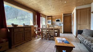 A wooden interior with a dining area, kitchen, and seating space.