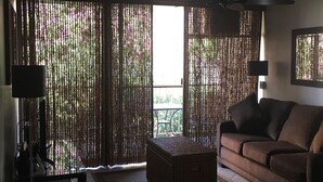 Een woonkamer met een bank, een bijzettafeltje en een plafondventilator.