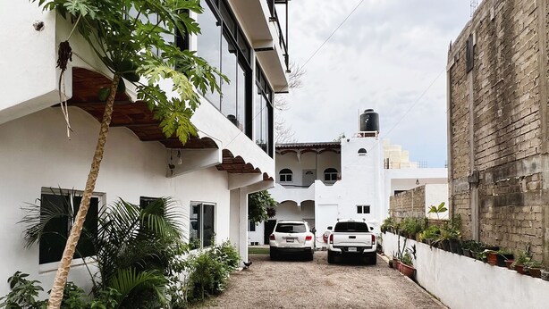 A narrow driveway leading to a white building with a small attached garage. - Casa Katrina #1 (Sayulita)