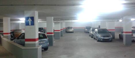 Een ondergrondse parkeergarage met meerdere rijen geparkeerde auto's en richtingsborden.