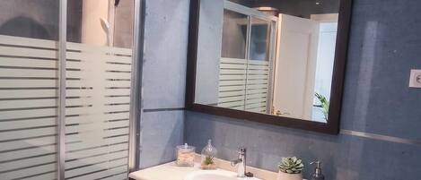 Une salle de bain moderne avec une douche à parois de verre, un grand miroir et un meuble-lavabo en bois.