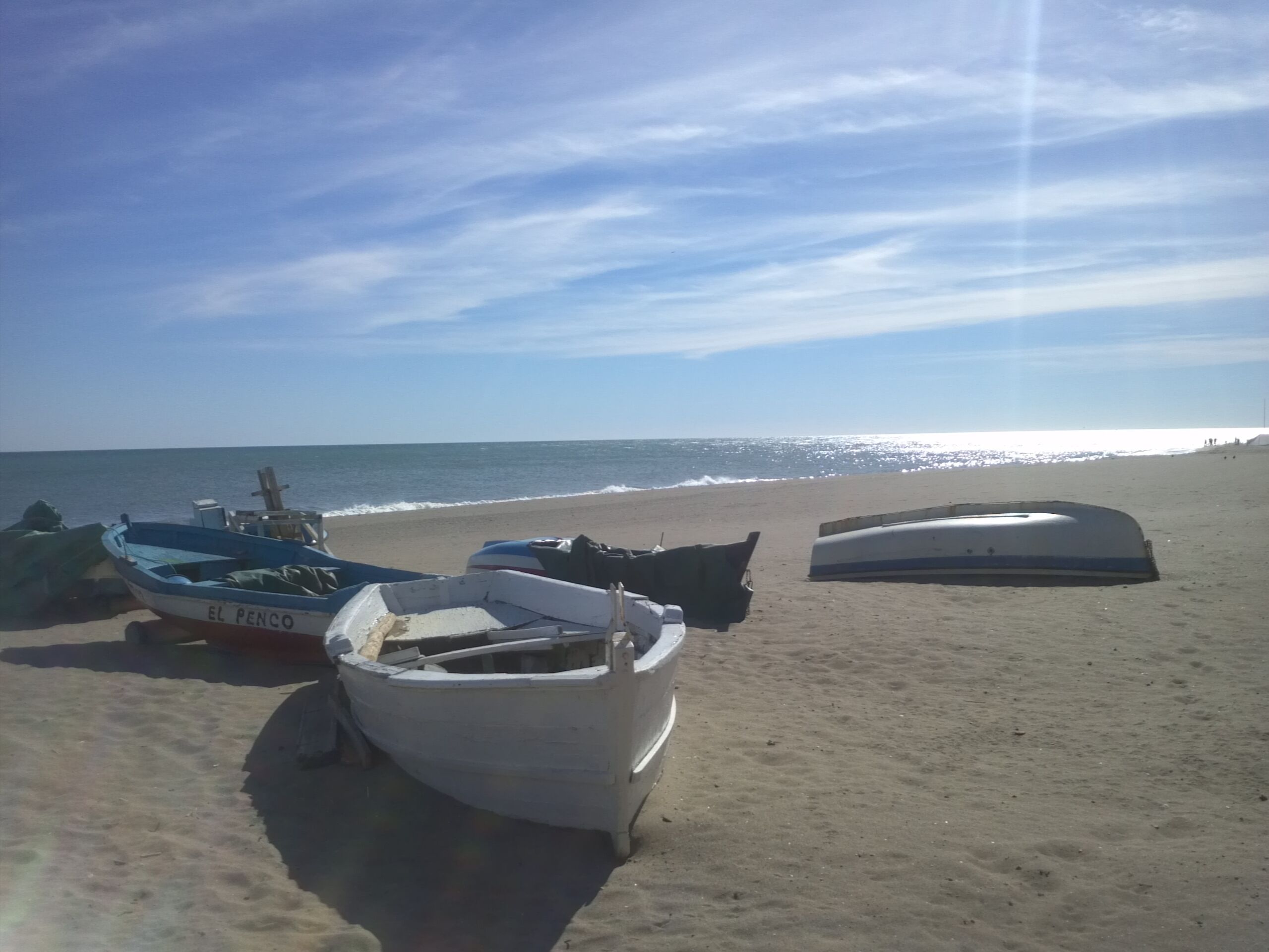Una playa con barcos y cielo despejado.