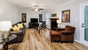 A living room with a ceiling fan, a fireplace, a television, and a sofa. - Beautiful Home Close To Everything (Greenville)