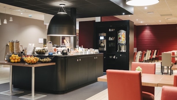 A modern restaurant interior with a central counter, dining tables, and chairs. - Ibis Rouen Centre Rive Gauche Mermoz (Rouen)
