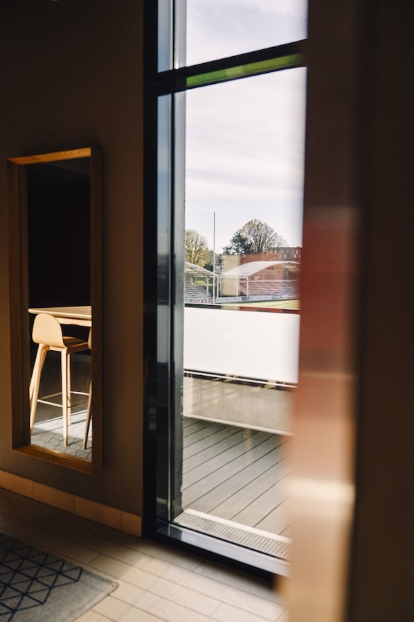 A modern room with a large window, a wooden floor, and a single chair. - Ibis Rouen Centre Rive Gauche Mermoz (Rouen)