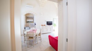 A bright, open-plan living space with a dining area, kitchen, and seating area. - La Torre nel Borgo (Melendugno)