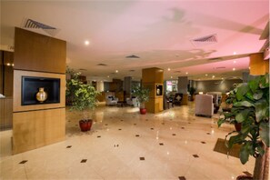 A spacious lobby with a polished marble floor, wooden reception desk, and potted plants. - Taleen Al Hasa (Al-Hofuf)