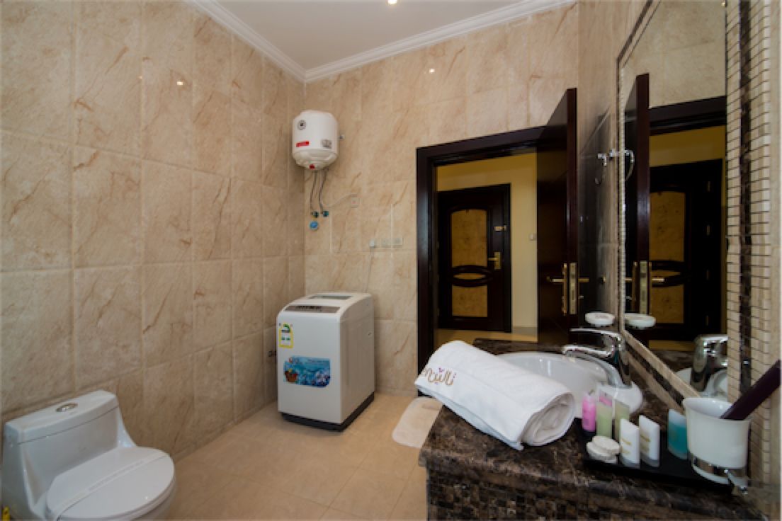 A bathroom with a toilet, a towel rack, a sink, a mirror, and a shower area.
