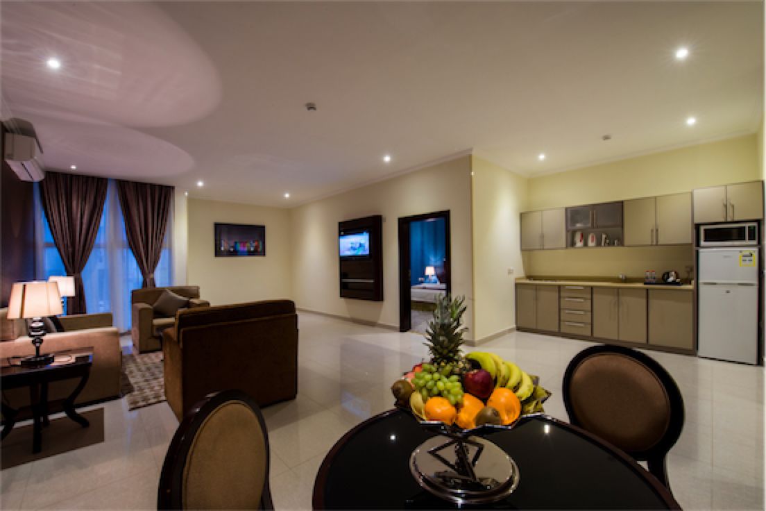 A modern hotel room with a dining area, a living room, and a kitchen.