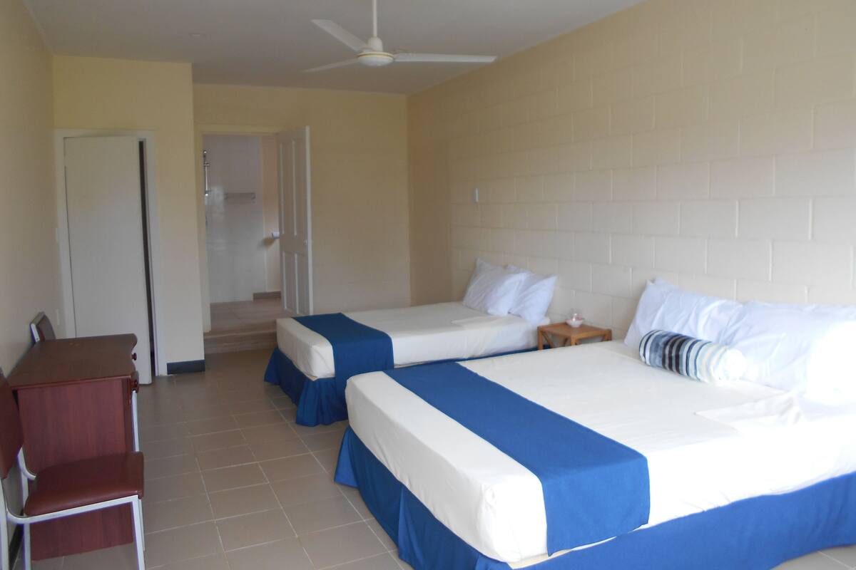 Une chambre d’hôtel avec deux lits, un bureau et une chaise.