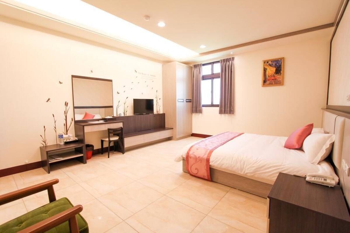 A modern hotel room with a bed, desk, chair, and a television.