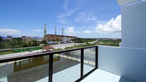 Un balcón con vistas a una zona industrial, que incluye edificios y chimeneas.