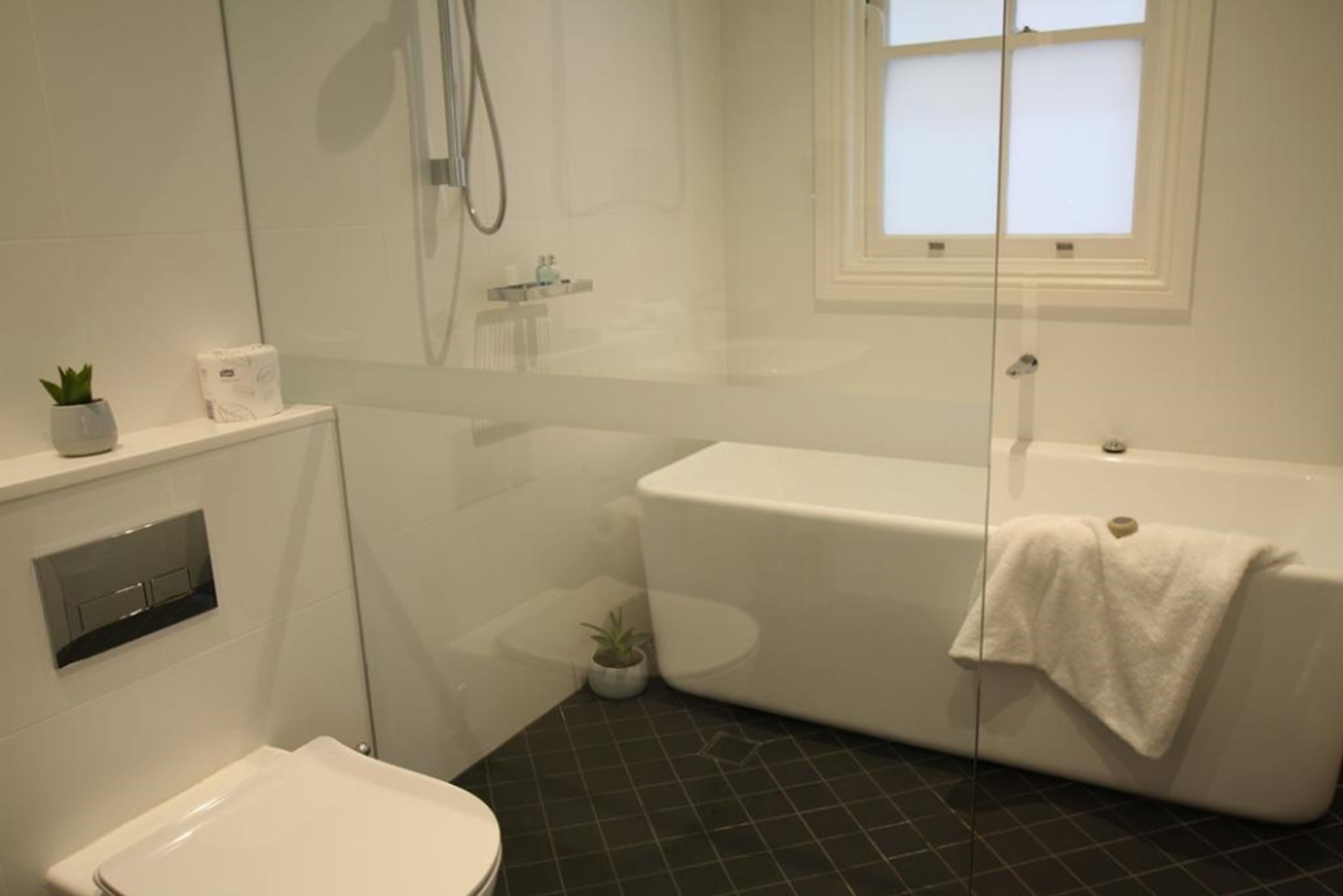 Een badkamer met een toilet, een douche en een bad.