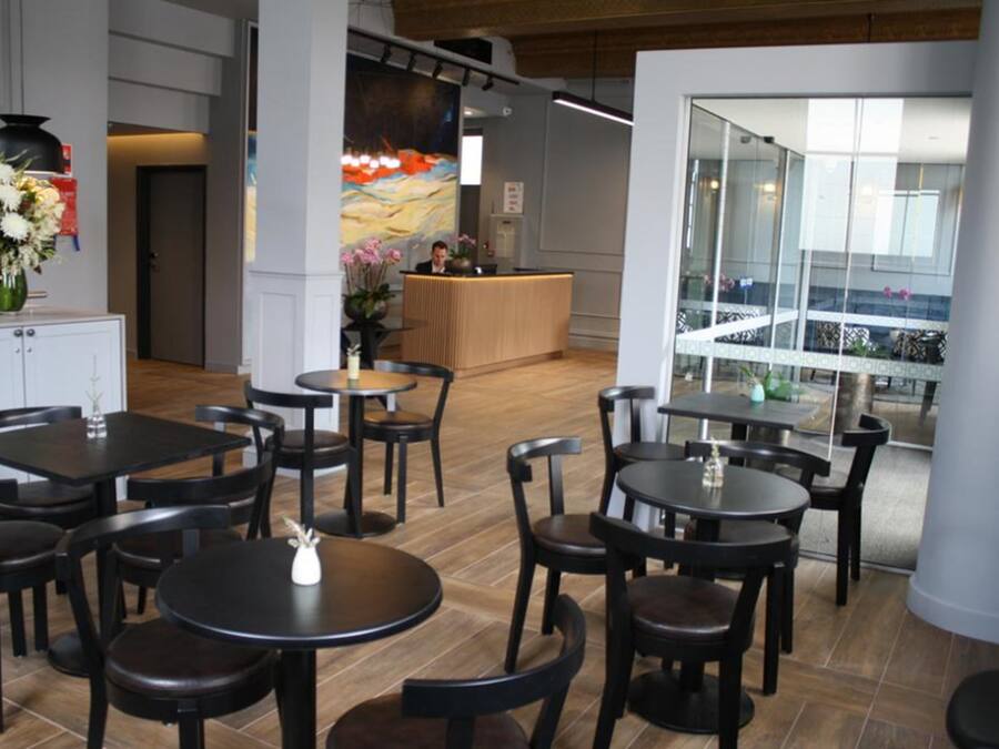 A modern hotel lobby with multiple seating areas, a reception desk, and a view of the interior through glass walls.