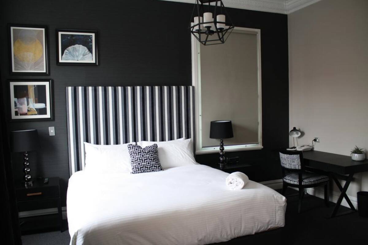 Een hotelkamer met een groot bed, een bureau, een stoel en een spiegel.