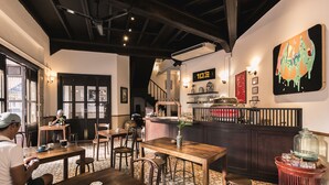 A restaurant with wooden tables and chairs, a bar area, and a large painting on the wall. - 103 - Bed and Brews (Bangkok)