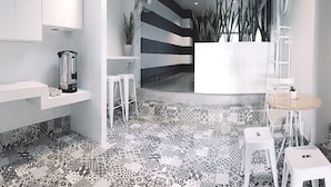 Una cocina moderna con armarios blancos, una cafetera y un piso estampado.