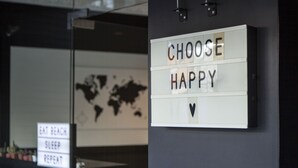 Una pared con letreros motivacionales que dicen "CHOOSE HAPPY" y "EAT BEACH SLEEP REPENT".