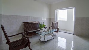 A spacious room with two wooden chairs, a glass coffee table, and a potted plant. - Kim Hong Anh Guesthouse (Phu Quoc)