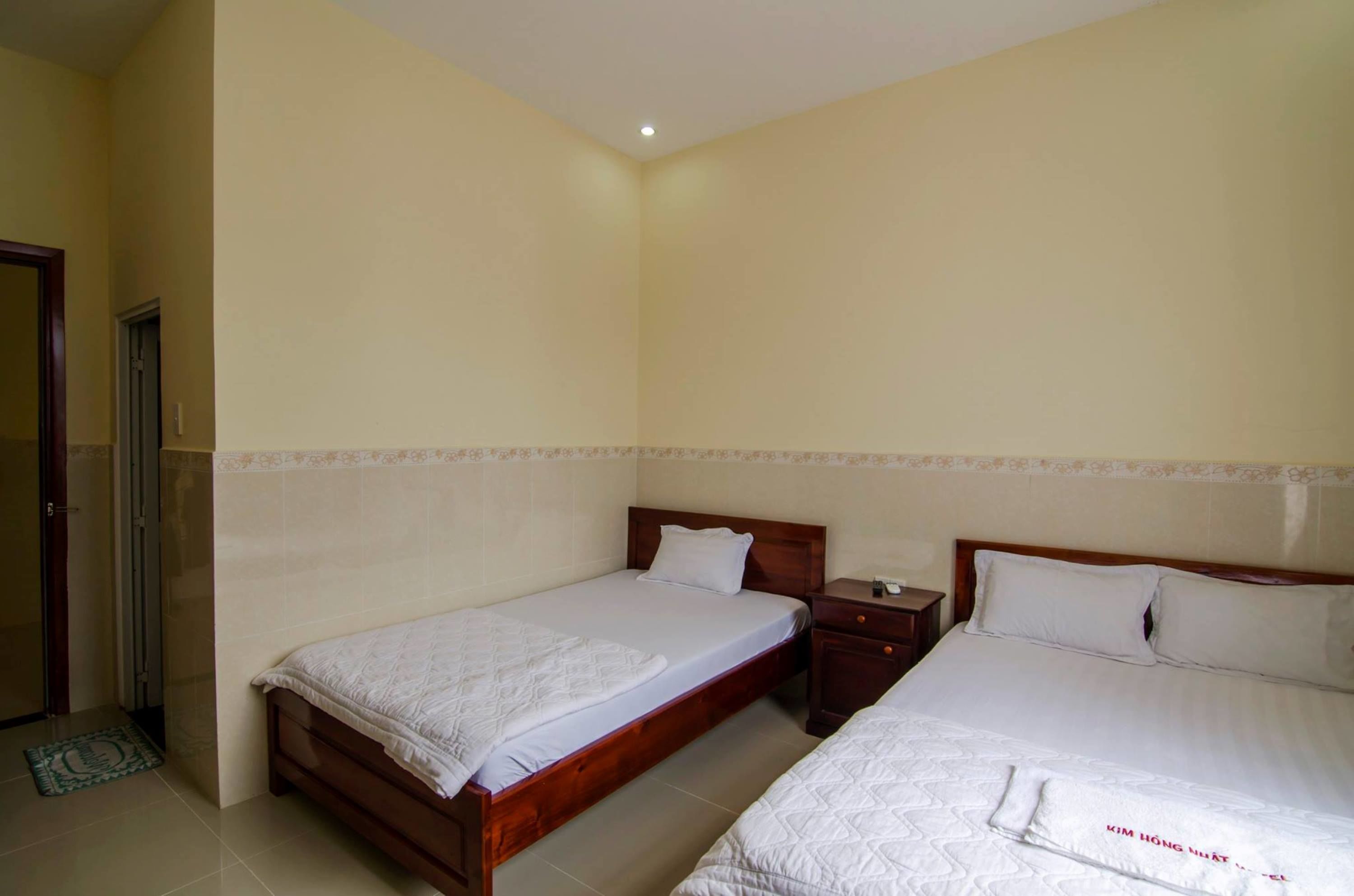 Un dormitorio con dos camas, cabeceras de madera, una mesita de noche y una puerta.