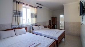 A hotel room with two beds, a TV mounted on the wall, and a window with curtains. - Kim Hong Anh Guesthouse (Phu Quoc)