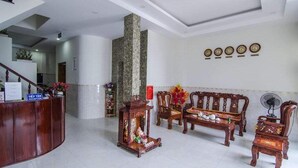 A reception area with a wooden reception desk, a stone pillar, and traditional wooden furniture. - Kim Hong Anh Guesthouse (Phu Quoc)