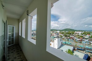 A balcony with a view of a coastal town, a tiled floor, and a door. - Kim Hong Anh Guesthouse (Phu Quoc)