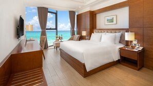 Een hotelkamer met een groot bed, een televisie, een bureau en uitzicht op de oceaan.