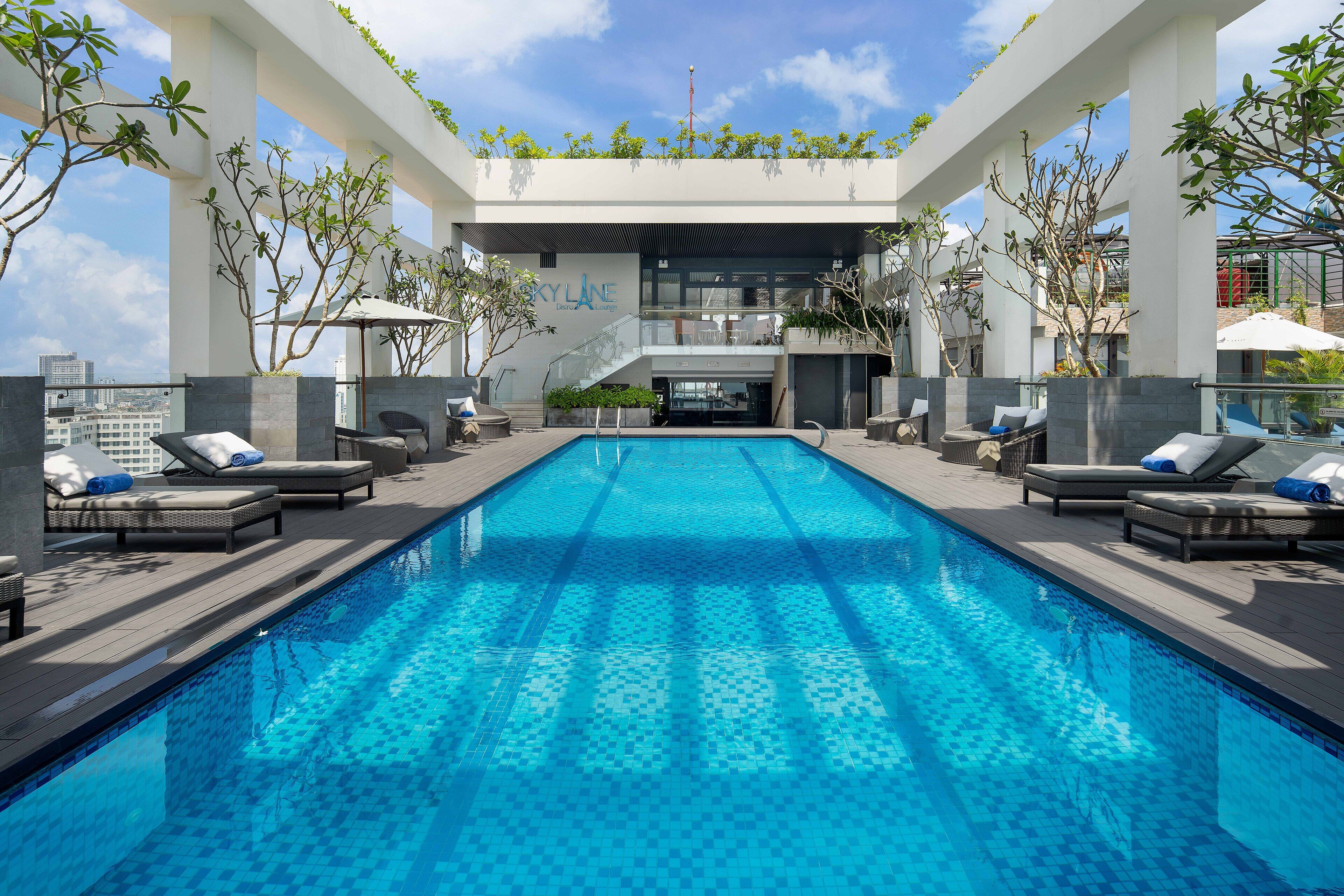 Una piscina en la azotea con sillones de descanso y una escalera que conduce a un nivel superior.