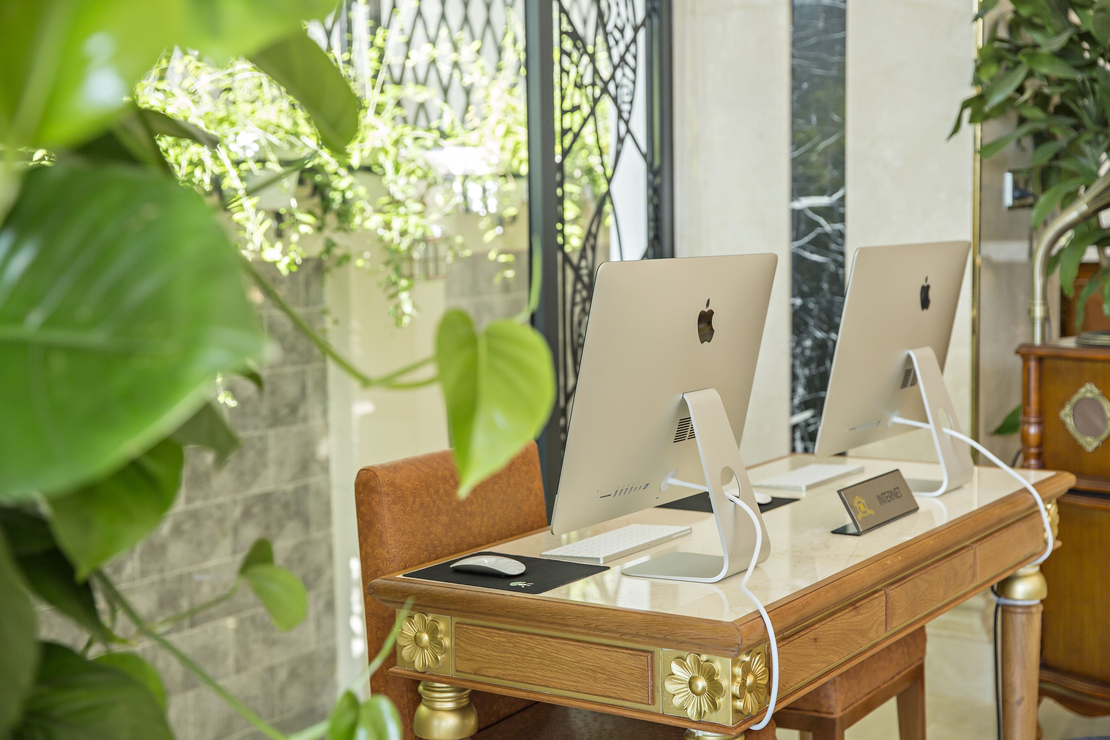 Two Apple iMac computers on a wooden desk with a nameplate, a keyboard, and a mouse.