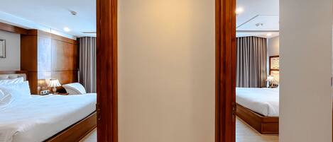 A hotel room with two beds, a wooden wardrobe, and a mirror reflecting the room.