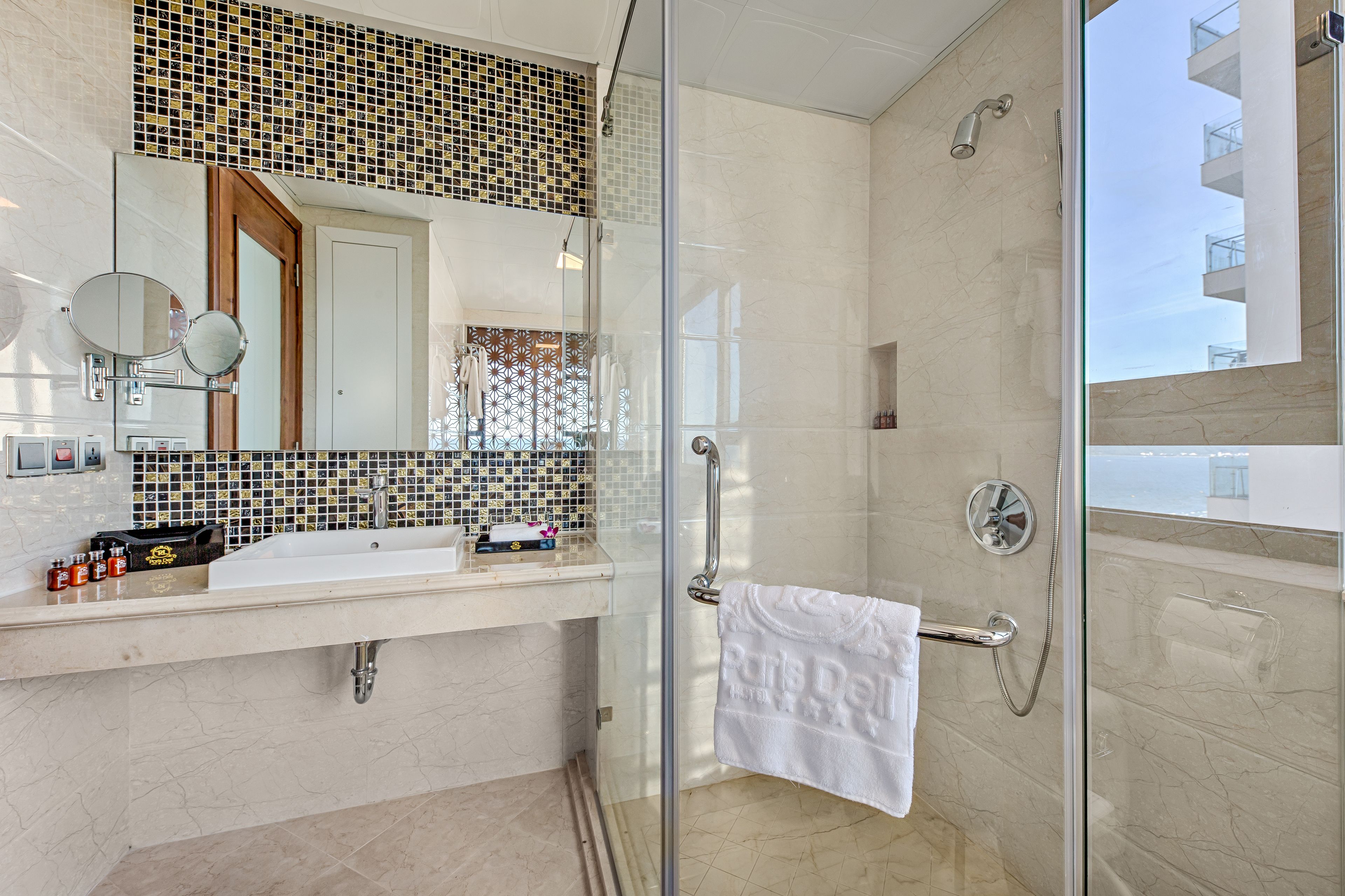 A modern bathroom with a glass-enclosed shower, a white sink with a mirror, and a tiled backsplash.