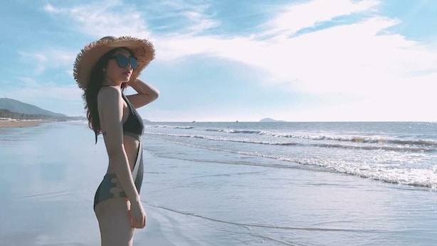 A person standing on a beach with a clear sky and ocean in the background. - Hai Tien Plaza Hotel (Hoang Tien)