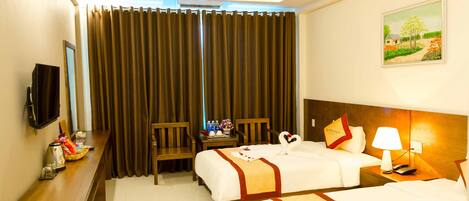 A hotel room with two beds, a desk, a chair, a TV, and a painting on the wall.