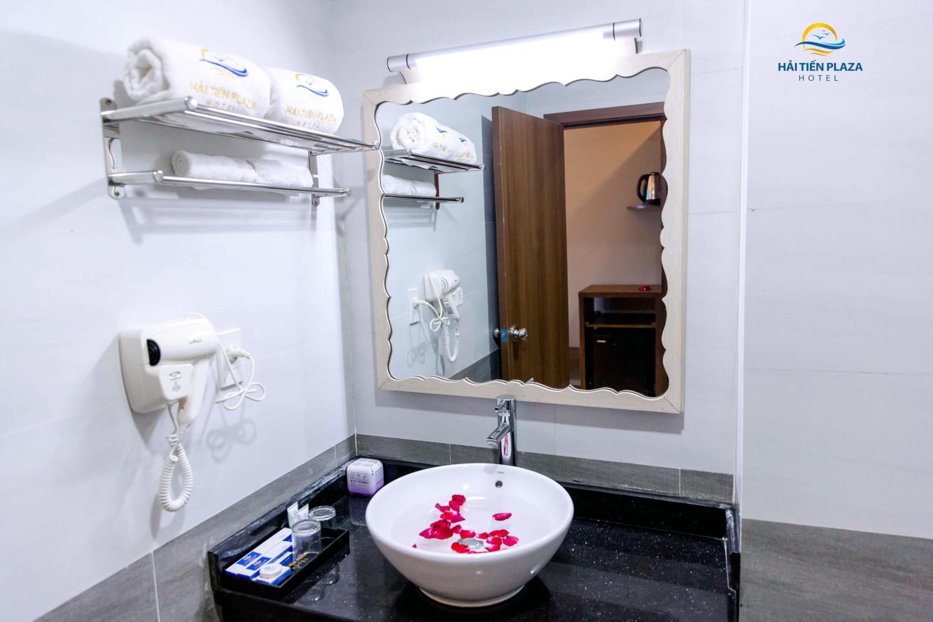 A bathroom with a white sink, a mirror, a towel rack, a hairdryer, and a phone.