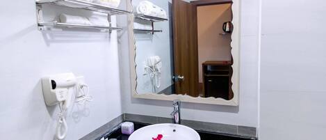 A bathroom with a white sink, a mirror, a towel rack, a hairdryer, and a phone.