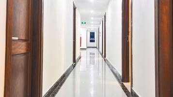 A long, well-lit hallway with wooden doors and a shiny tiled floor.