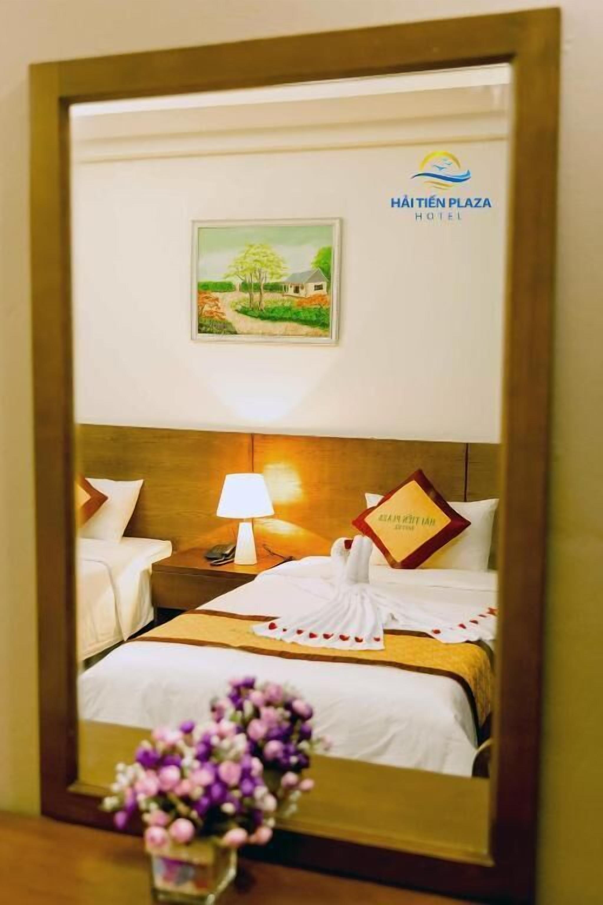 A hotel room with a bed, a nightstand, a lamp, and a framed picture on the wall.