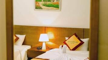 A hotel room with a bed, a nightstand, a lamp, and a framed picture on the wall.