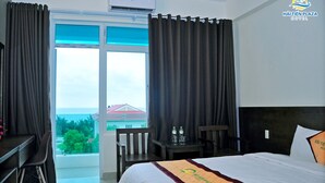 A hotel room with a bed, a desk, a chair, and a view of the sea. - Hai Tien Plaza Hotel (Hoang Tien)