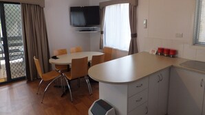 Una cocina moderna con comedor, un televisor de pantalla plana sobre la encimera y una puerta corrediza de vidrio que da a un espacio exterior.