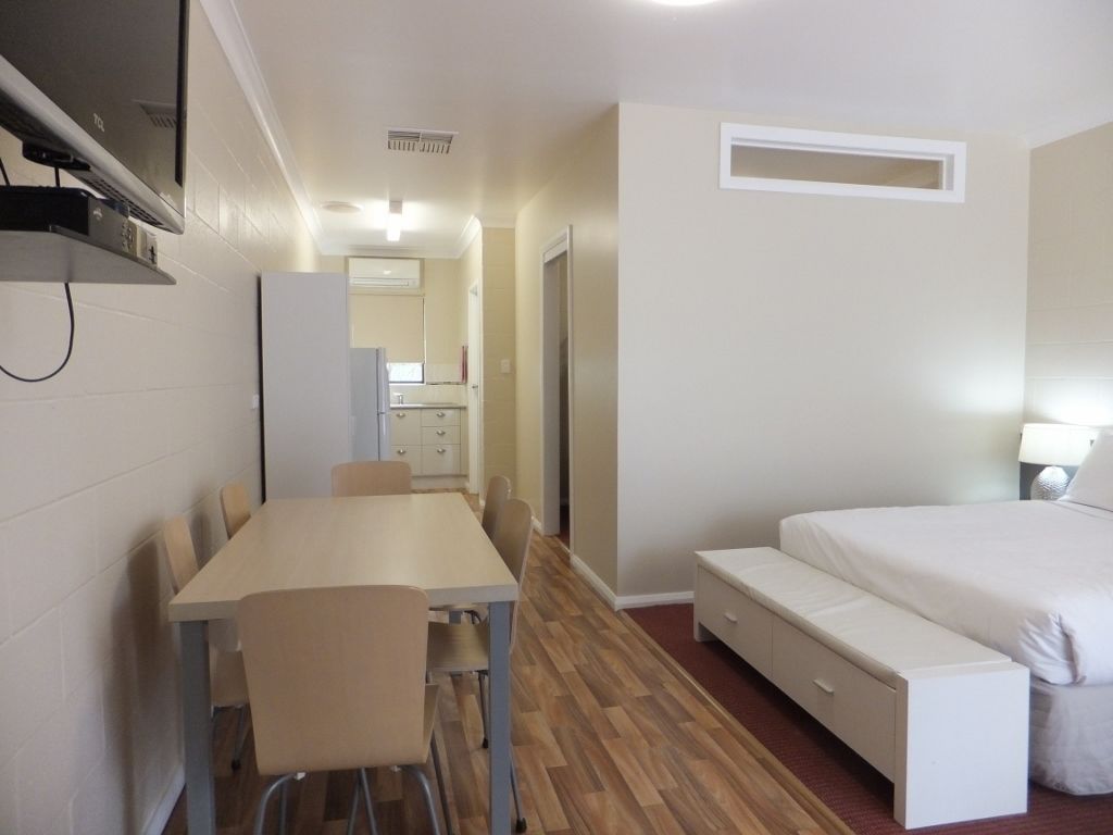A compact room with a bed, a small desk, and a chair.