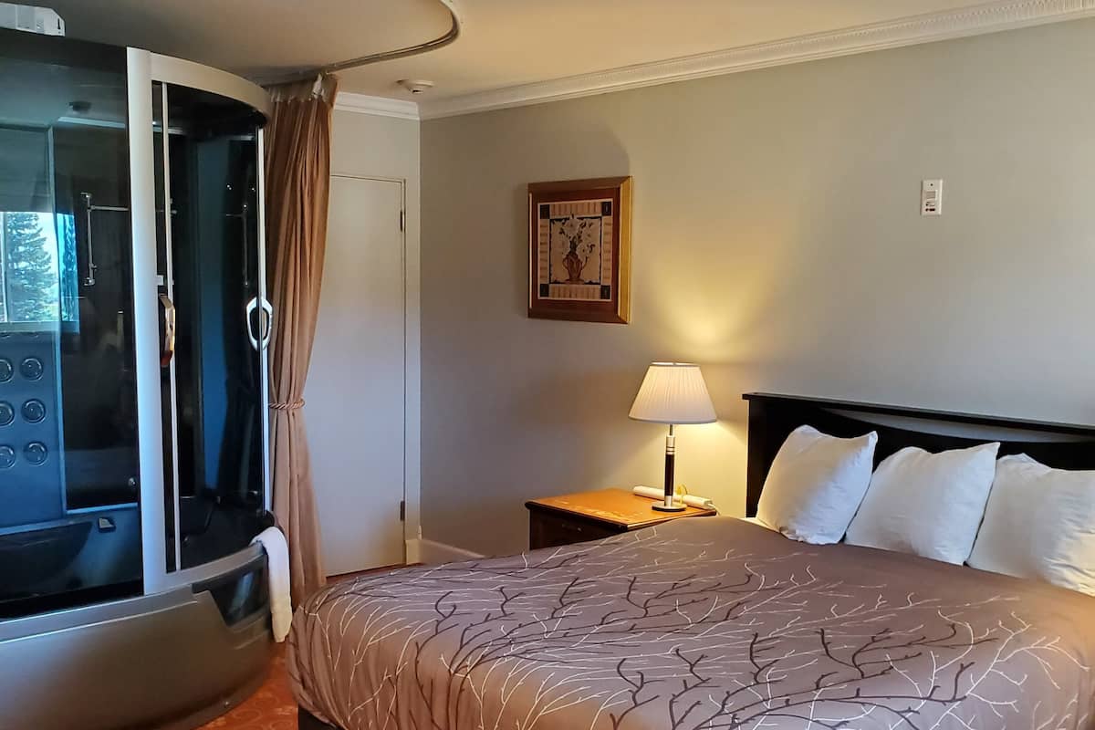 A hotel room with a bed, a desk, a lamp, a picture on the wall, and a sliding door.