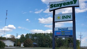 Letrero de StayEasy Inn con un símbolo de clima, un logo de canales de cine, y menciones de Wi-Fi e internet gratuitos.