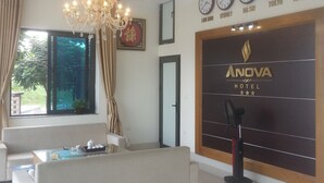 A modern hotel lobby with a chandelier, a sofa, a massage chair, and clocks displaying times from various cities. - AVS NOIBAI HOTEL  (Hanoi)