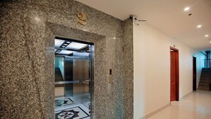 A modern elevator with a granite wall, a visible floor number, and a clean, tiled floor. - AVS NOIBAI HOTEL  (Hanoi)