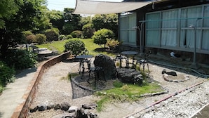 A traditional Japanese building with a garden, outdoor seating, and a gravel path. - YOKOSO Ryokan (Beppu)