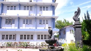 A multi-story building with a blue facade, large windows, and a decorative swan statue. - Jor Koo City Hotel (Ban Chang)