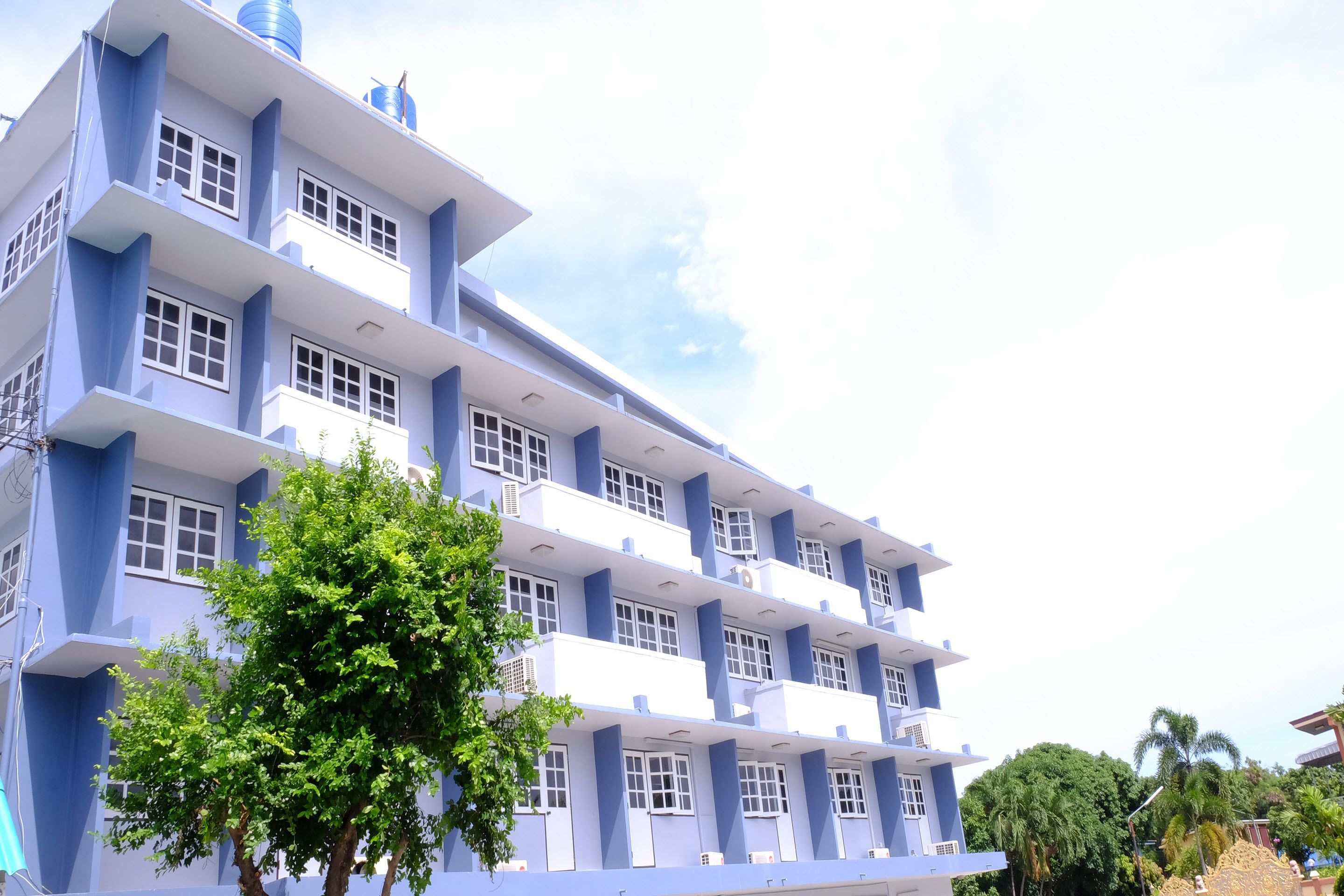 A multi-story building with a blue and white color scheme, featuring balconies and windows.